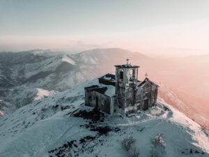 Kirche auf einer schneebedeckten Bergspitze im Sonnenaufgang